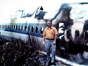 1 of 4 survivors standing by wreckage